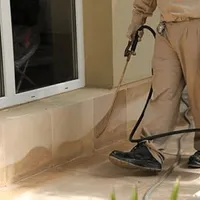 General pest control technician spraying exterior perimeter around a home in San Diego, CA