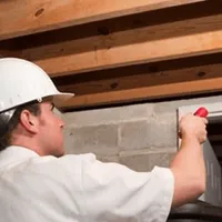 Termite inspection technician checking a basement wall and framing for termite activity in San Diego, CA